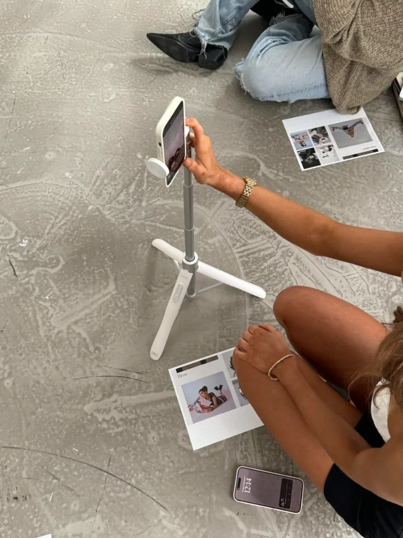 A phone on a tripod set up for a content shoot, with printed moodboards on the floor
